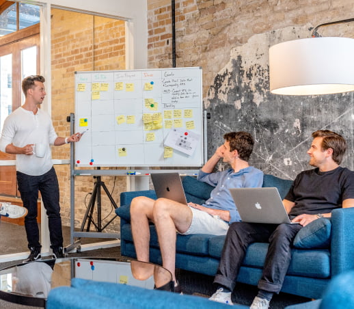 Whiteboarding session with a standing presenter and two other participants sitting on a couch