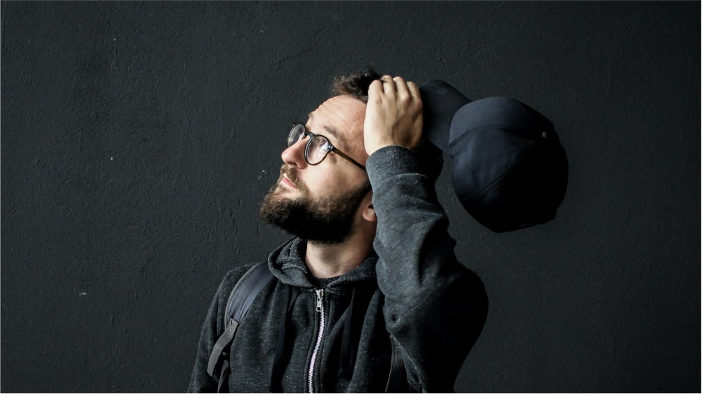 Man scratching his head and looking upward while thinking