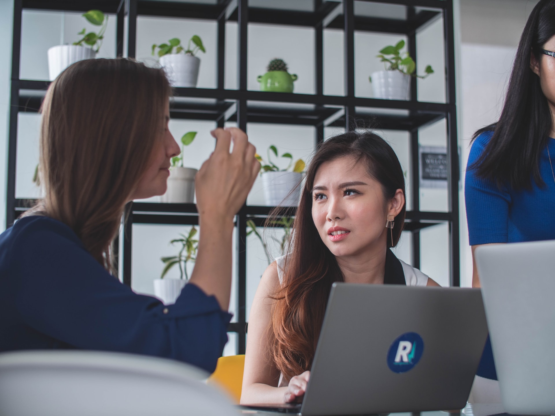 Two women having a serious discussion in front of a laptop.