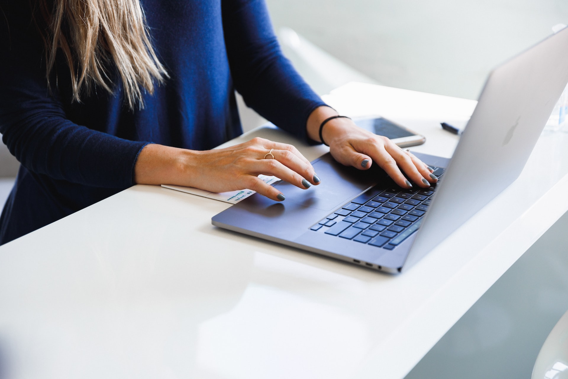 Woman in a blue shirt typing on a laptop