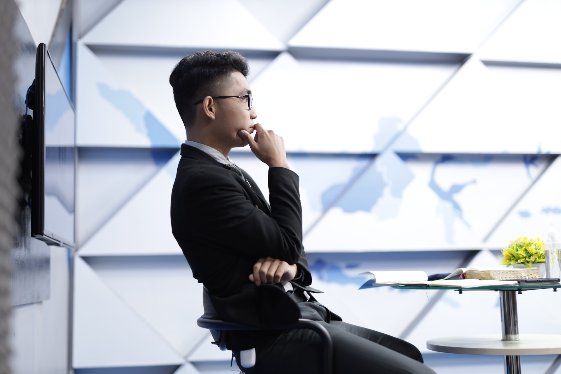 A man in a suit sitting in an office chair and thinking through a difficult decision.