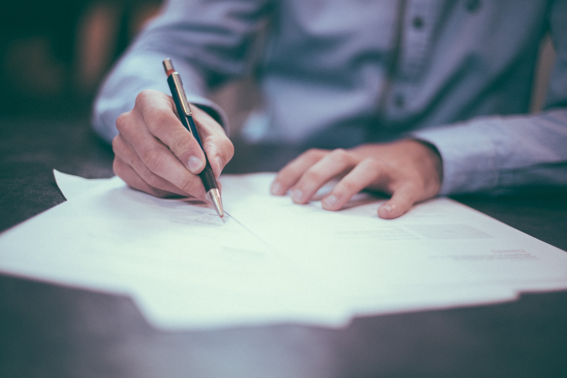 A man writing on a stack of papers