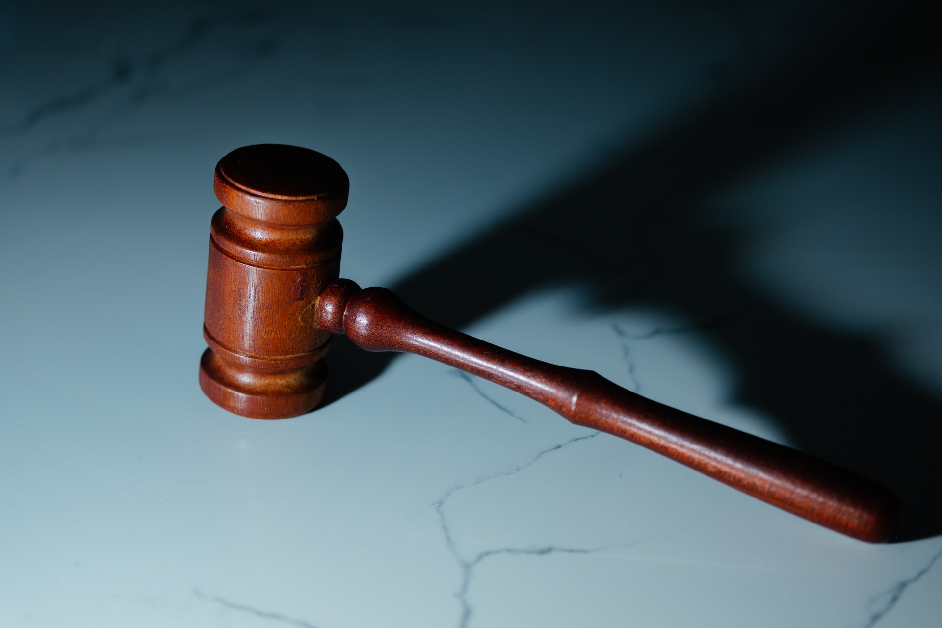 A wooden gavel resting on a marble surface.