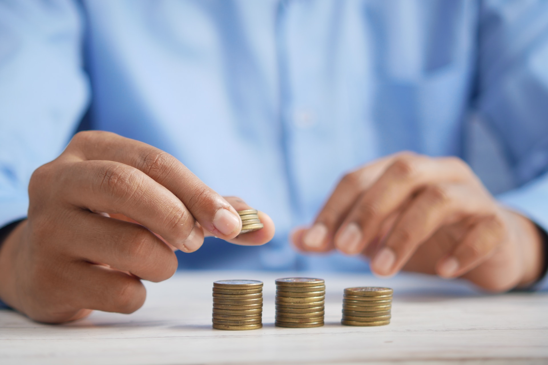 A person counting and stacking coins on a white table