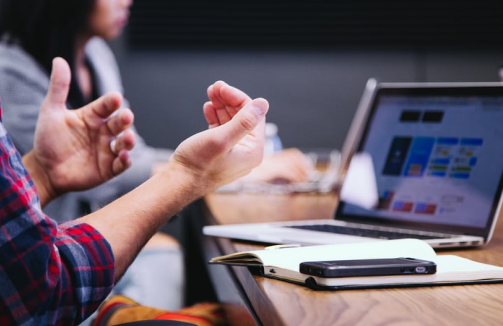 Person gesturing with their hands while seated at a table